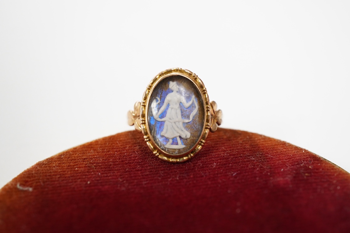 An early 20th century 9ct oval ring, decorated with the figure of a lady in relief, on a butterfly wing ground, beneath a glazed panel, size K, gross weight 2.3 grams.